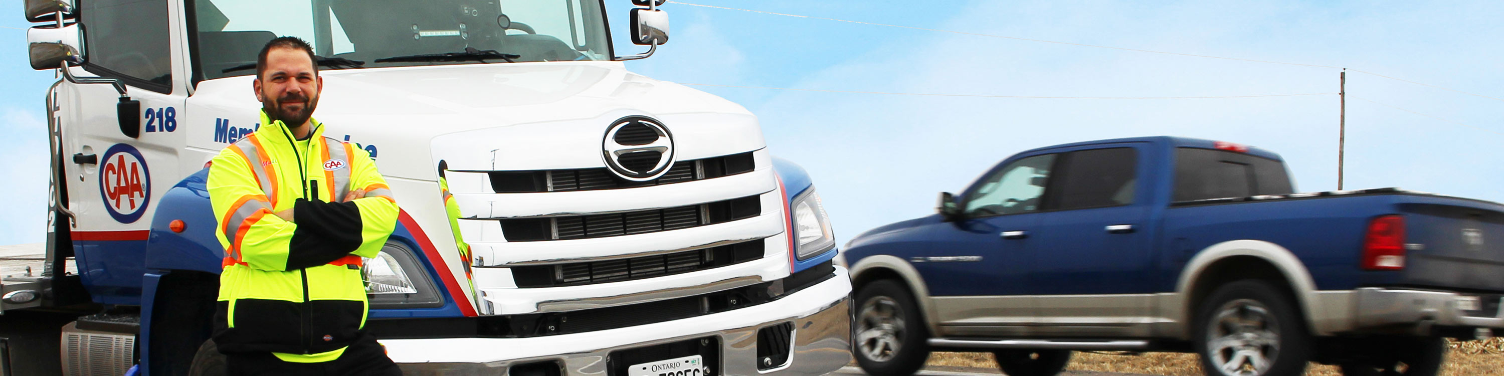 CAA tow truck operator on side of road passed by a truck.