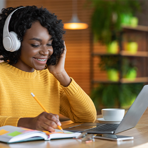 Woman listening to music through headphones while on her laptop