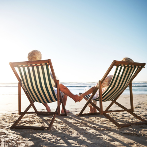 rearview shot of a senior couple relaxing in beach chairs while looking at the view over the water