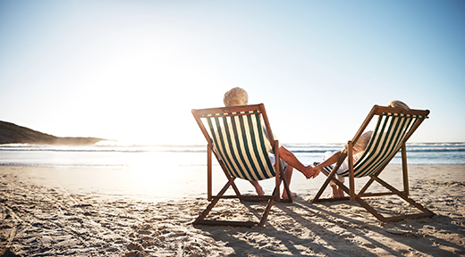 rearview shot of a senior couple relaxing in beach chairs while looking at the view over the water