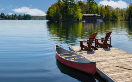 Two Adirondack chairs on a wooden dock overlook the waters of a Muskoka lake in Ontario, Canada