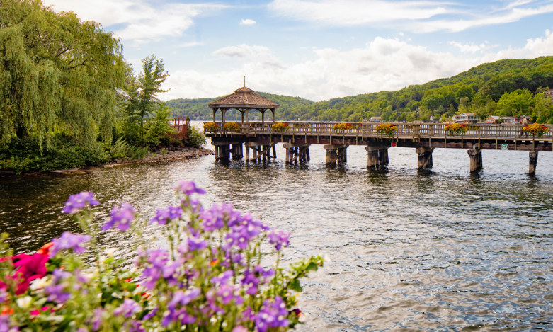Panoramic view of North Hatley's promenade pier and gazebo in Eastern townships Quebec with potted flowers in the foreground.