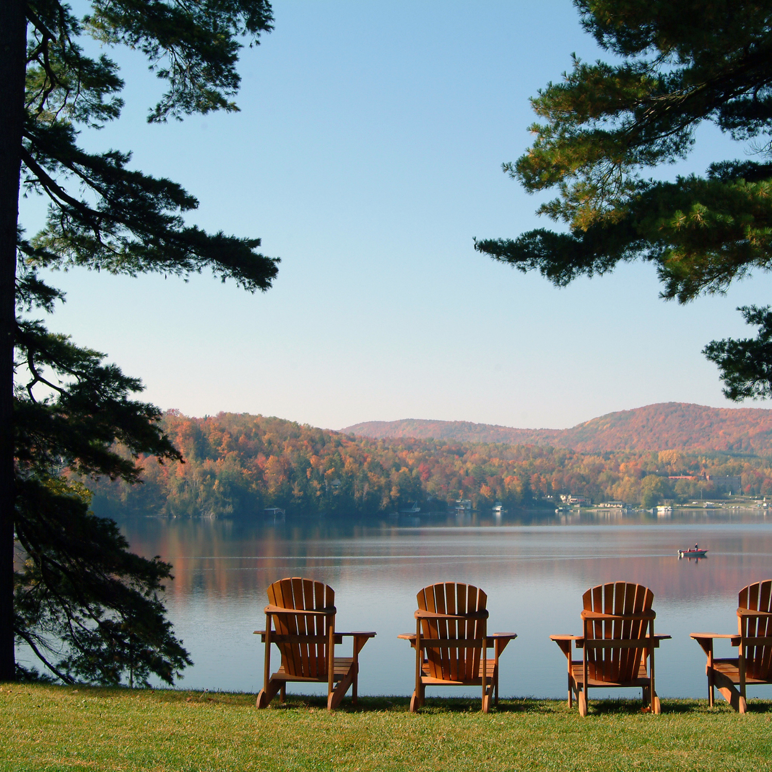 4 chairs facing the beautiful lake Massawippi in the Eastern Townships, Québec. Photo taken on a calm tranquil colorful morning during the peak autumn foliage season in Ayers Cliff, Quebec.