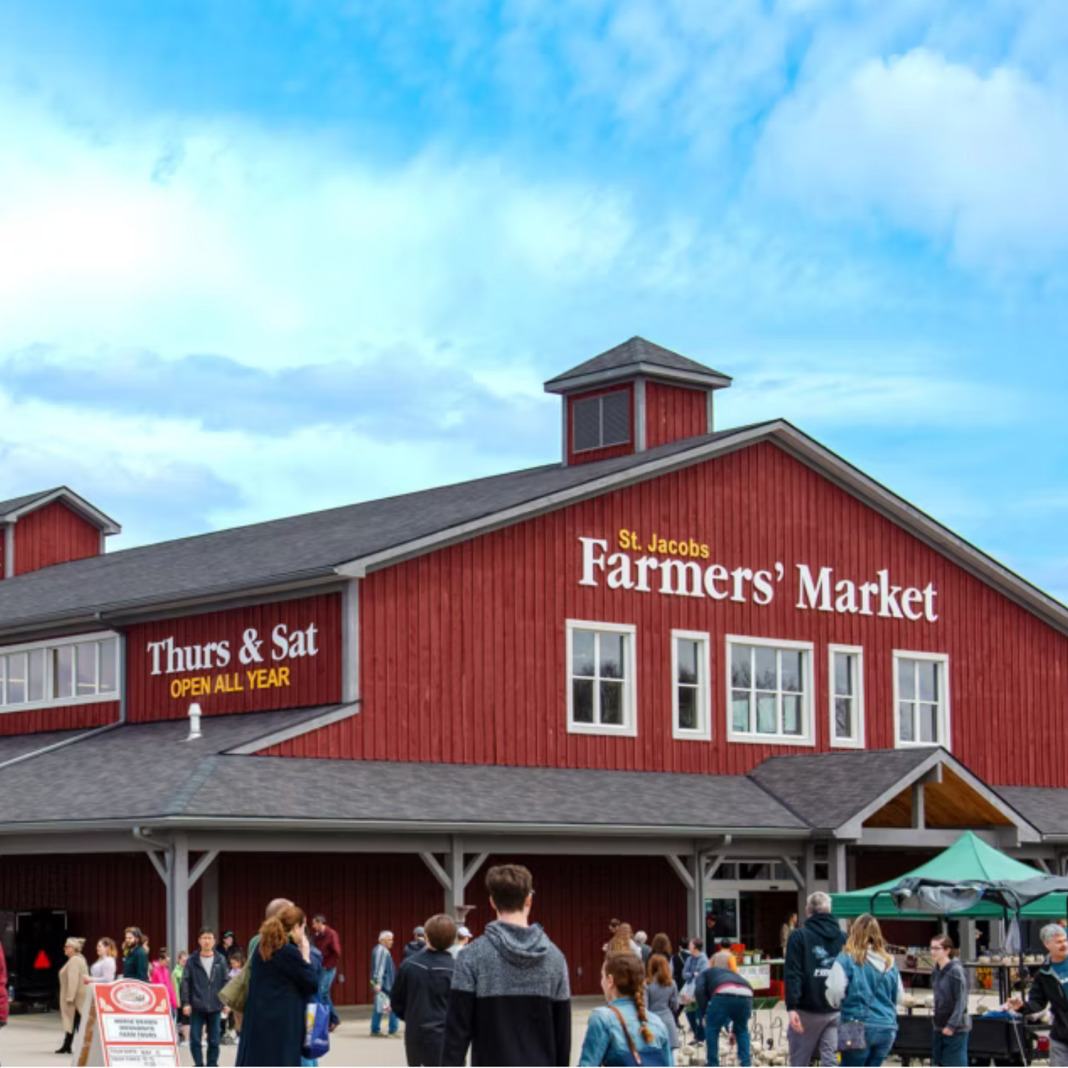 St Jacobs Farmers market building with people out front shopping at outdoor booths and walking into the building