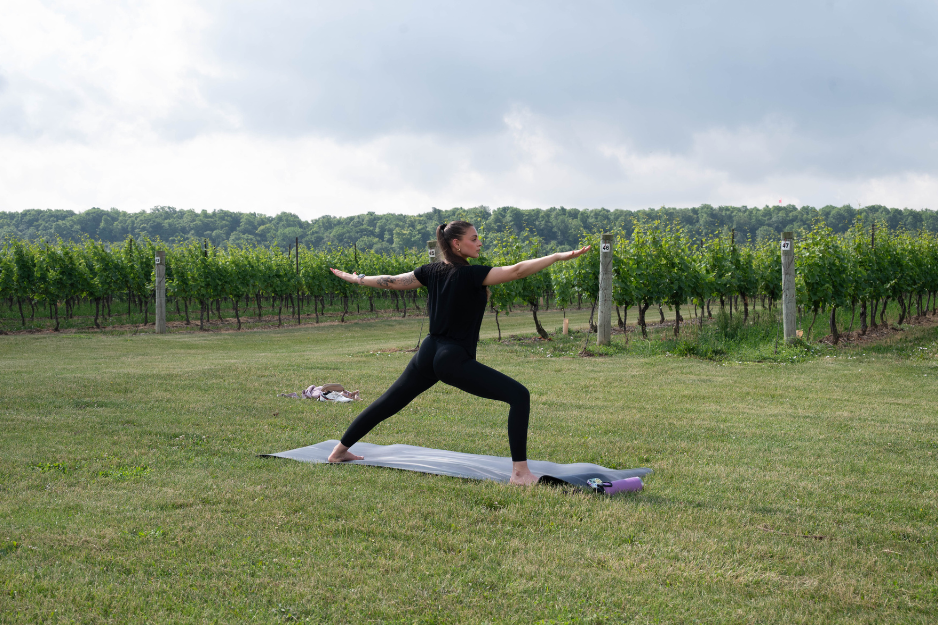 woman outside on nice day doing yoga in vineyard