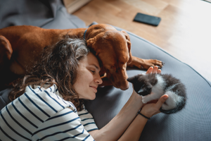 young woman with a Hungarian Pointer dog and a small kitten in her arms lying at home in a room