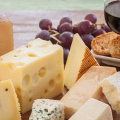 Various types of cheese accompanied by a glass of wine