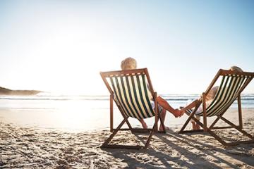 rearview shot of a senior couple relaxing in beach chairs while looking at the view over the water