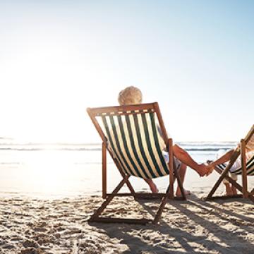 rearview shot of a senior couple relaxing in beach chairs while looking at the view over the water