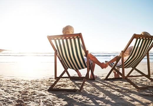rearview shot of a senior couple relaxing in beach chairs while looking at the view over the water