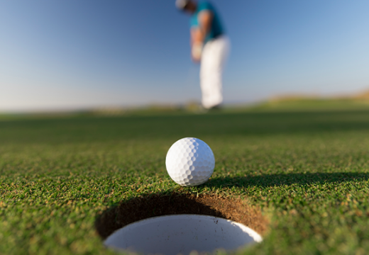 Golf ball about to fall in hole