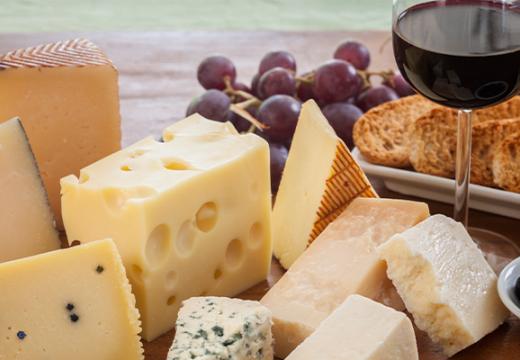 Various types of cheese accompanied by a glass of wine