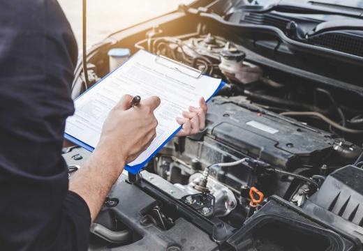 Services car engine machine concept, Automobile mechanic repairman checking a car engine with inspecting writing to the clipboard the checklist for repair machine, car service and maintenance.