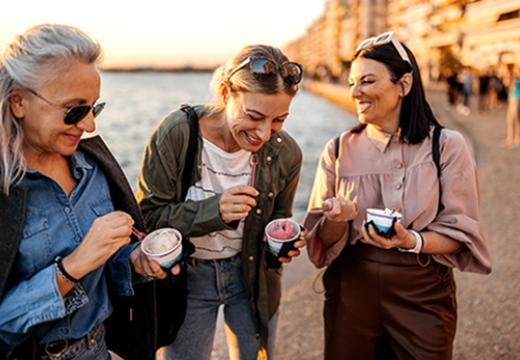 Group of female friends having ice cream by the sea in the city