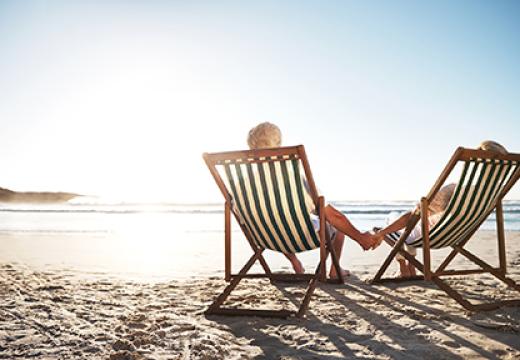 rearview shot of a senior couple relaxing in beach chairs while looking at the view over the water