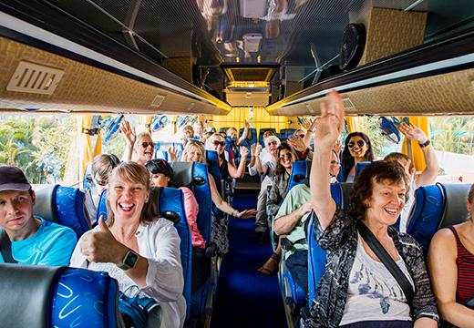 Group on tour bus smiling with thumbs up