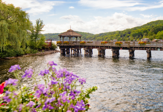 Panoramic view of North Hatley's promenade pier and gazebo in Eastern townships Quebec with potted flowers in the foreground.