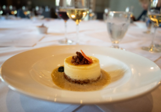 gourmet dessert on plate with wine glasses behind it on table