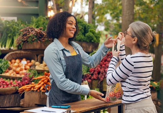 woman purchasing produce at an outdoor market