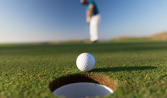 Golf ball about to fall in hole