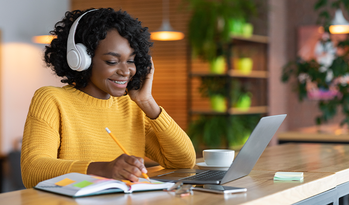 Woman listening to music through headphones while on her laptop