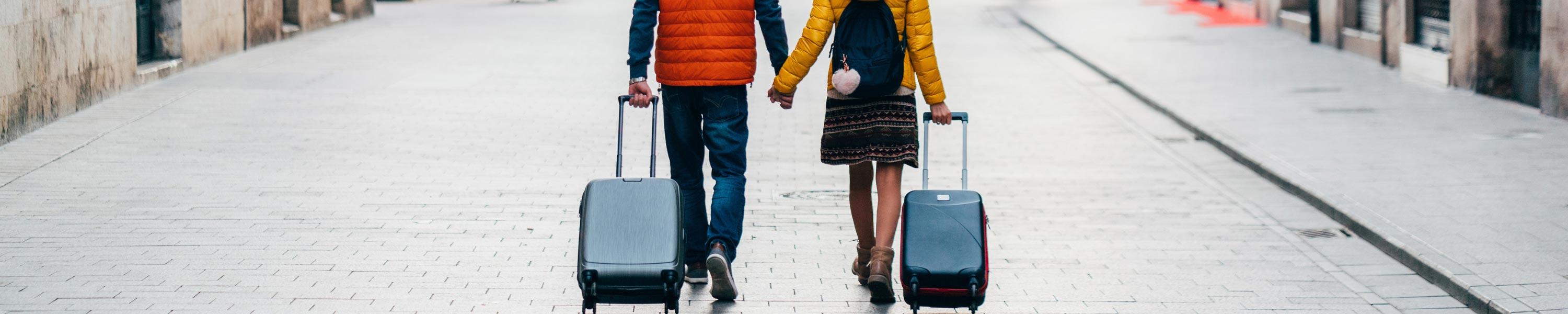 couple holding hands and pulling their suitcases