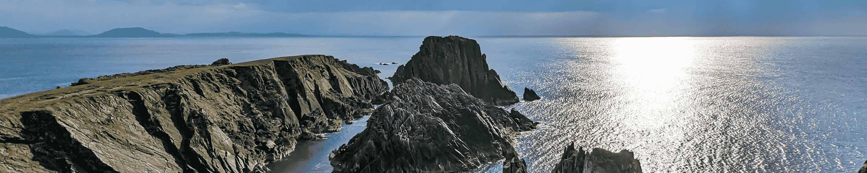 Irish landscape scene with sunlight shining through the clouds above the rocky cliffs and ocean at Malin Head in Ireland