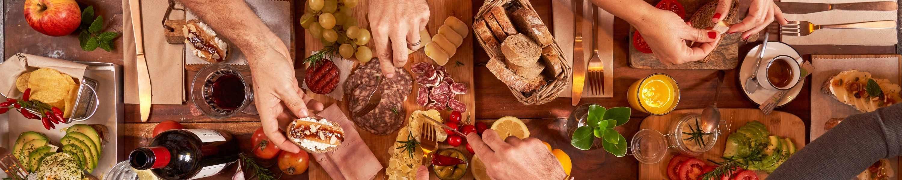 people taking items off of a long charcuterie board with various food items