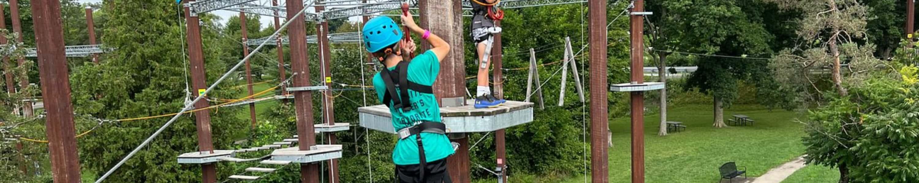 A child climbing across a high ropes course