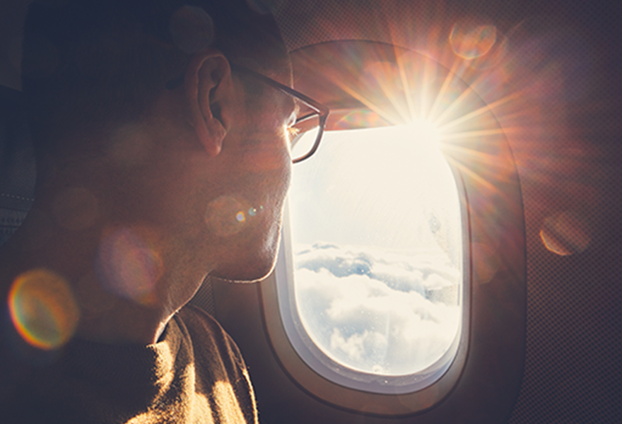 Young man with glasses looking out airplane window