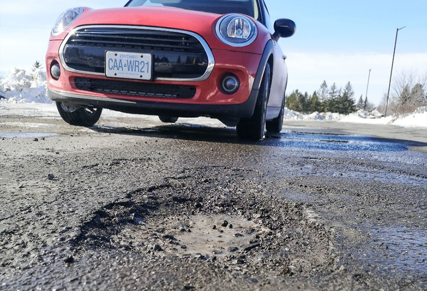Mini Cooper car parked next to pot hole on Niagara road.