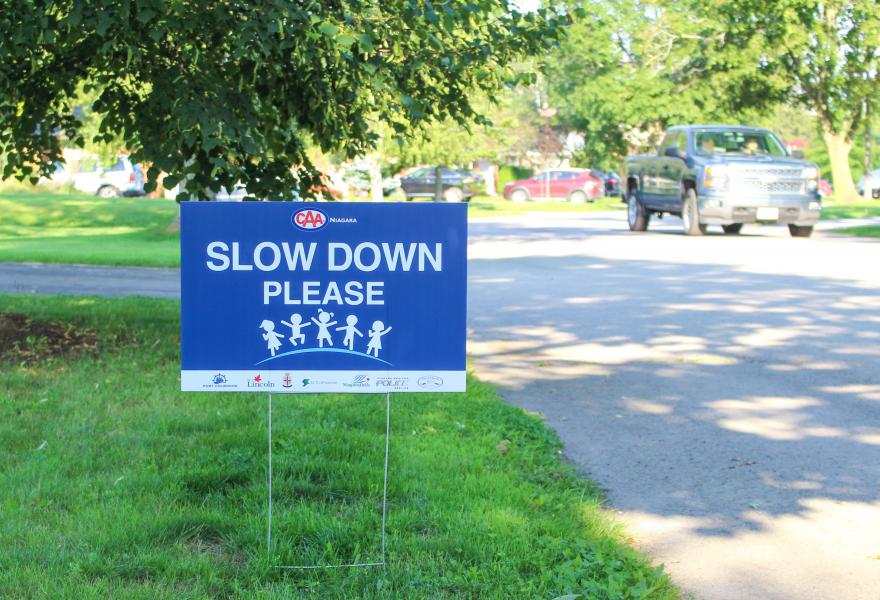 CAA 'Slow Down' road safety sign on lawn.