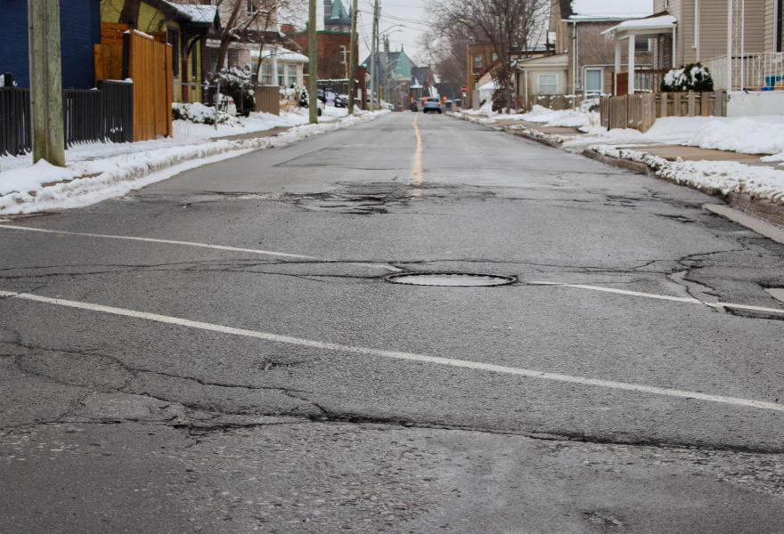 A street in St. Catharines with cracked pavement and potholes 