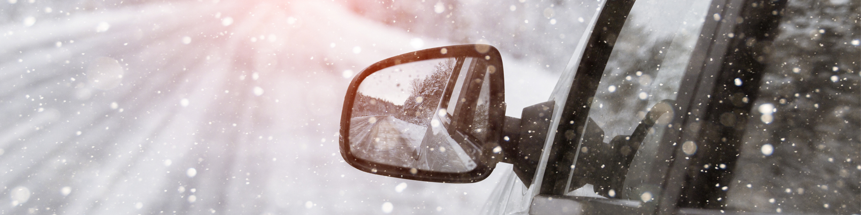 The winter road is reflected in the car's rear-view mirror