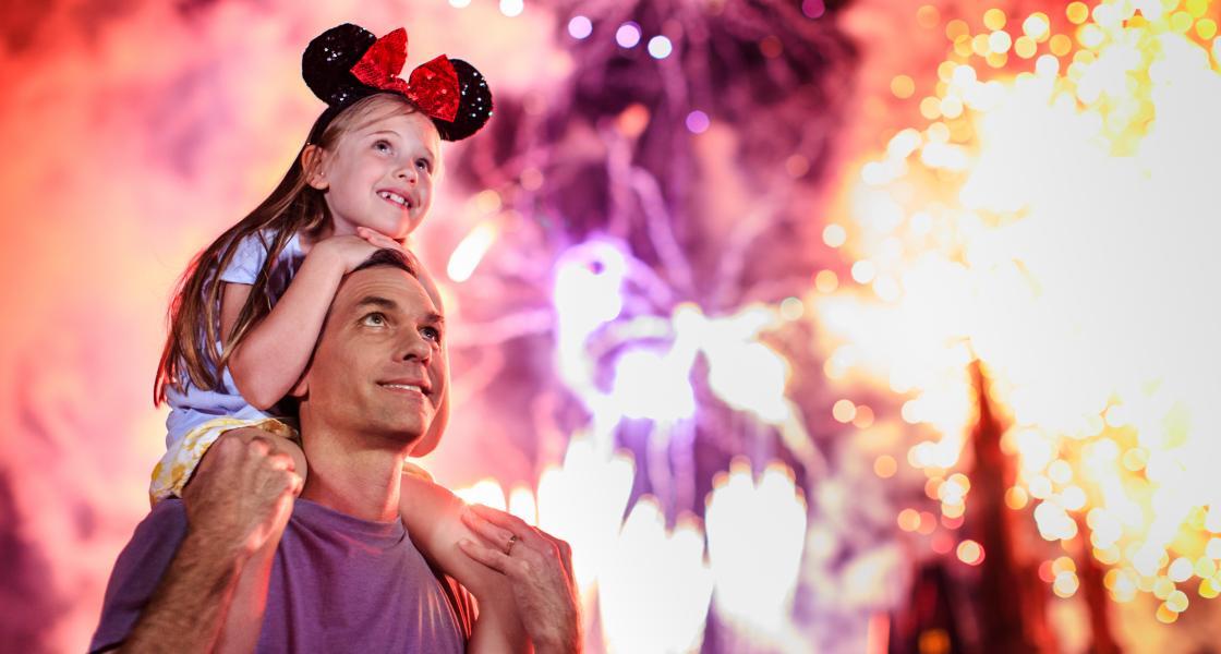 Father and daugtwe watching fireworks at a Disney Park